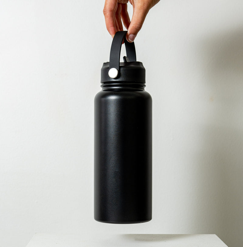 Byron 1L Drink Bottle Black held by a hand up close